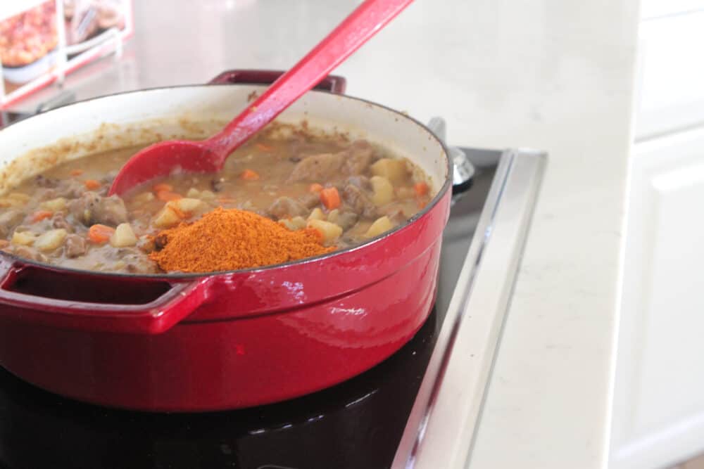 adding seasonings to pot of beef stew