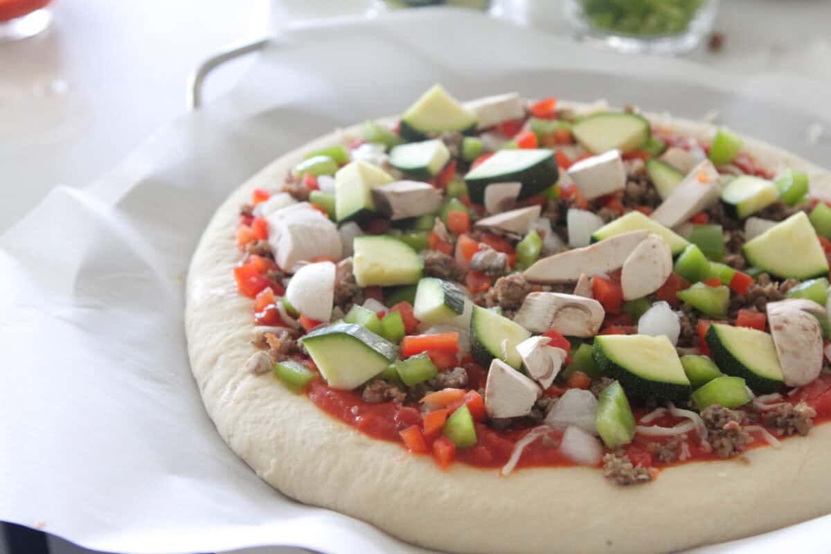 vegetables added to top of supreme pizza before cooking