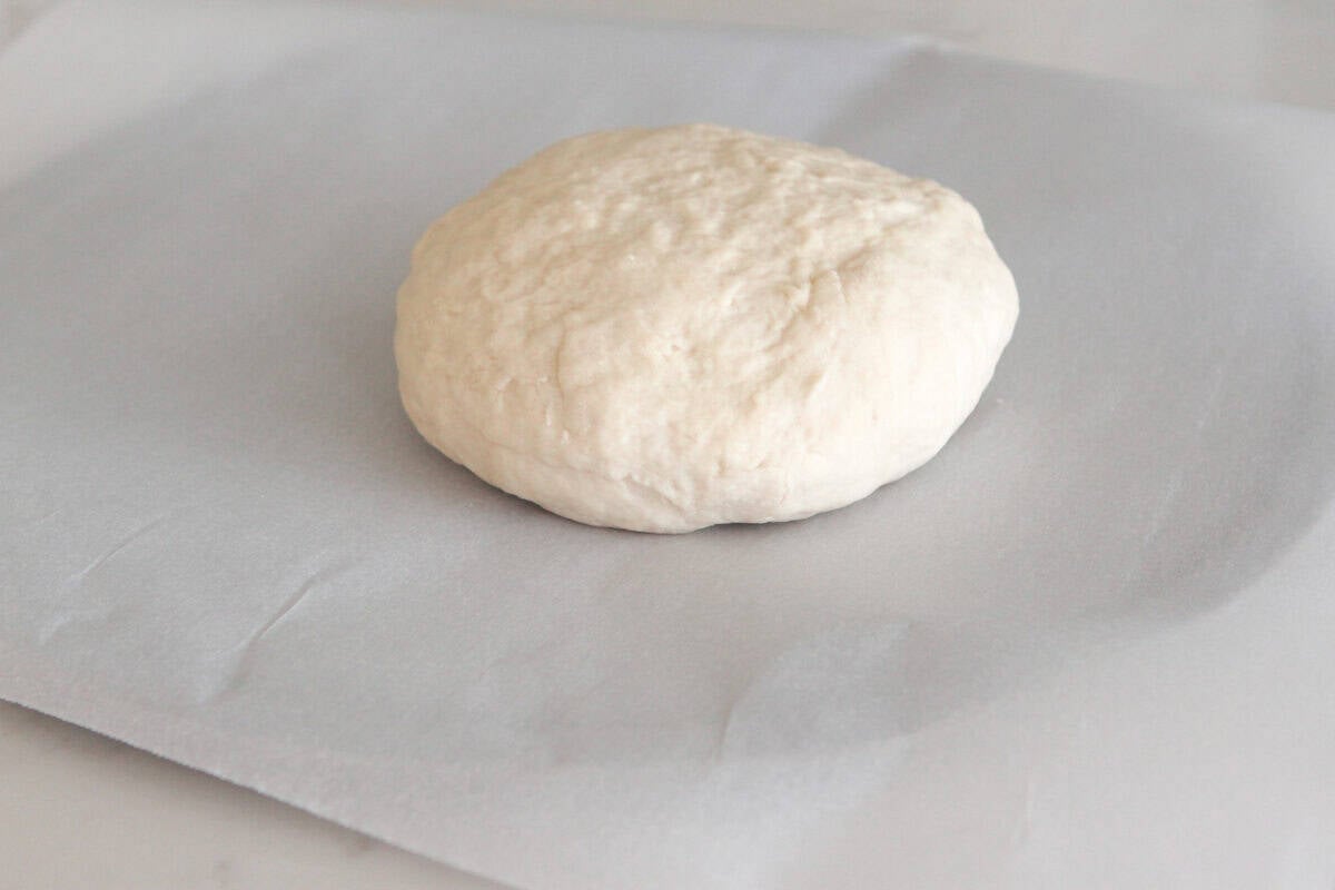 pizza dough rolled into a ball on pizza pan
