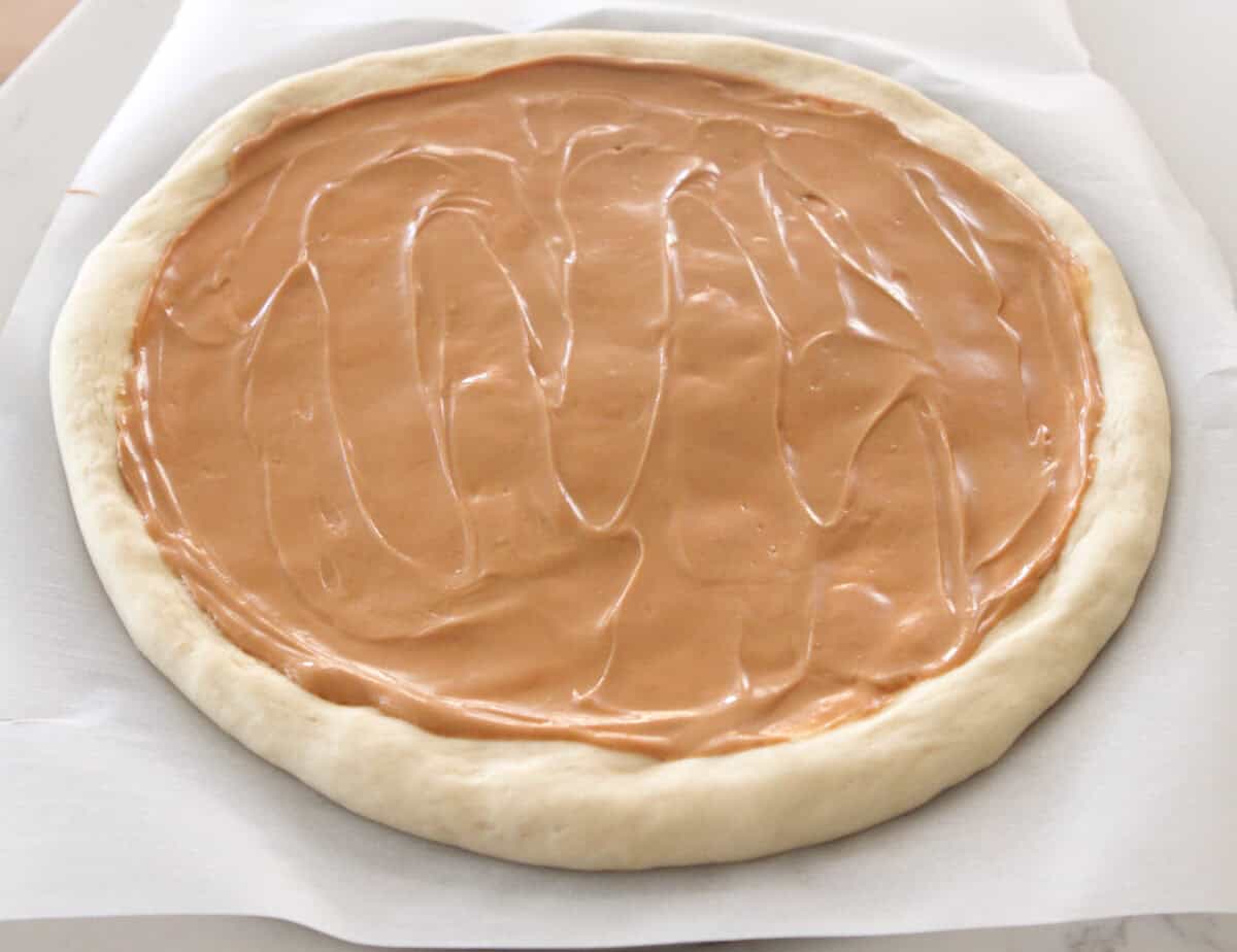 peanut butter spread over pizza dough on pizza pan