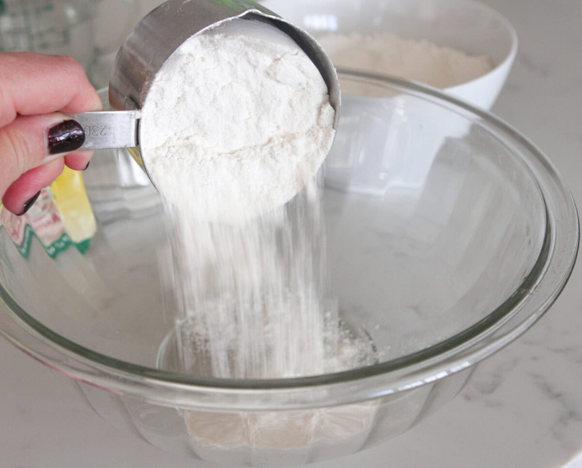 adding flour to a large mixing bowl