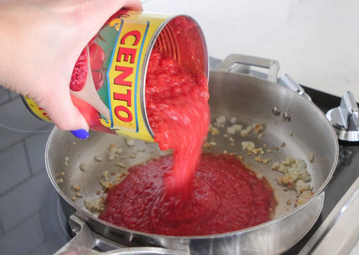 pouring crushed tomatoes in pot for rigatoni sauce