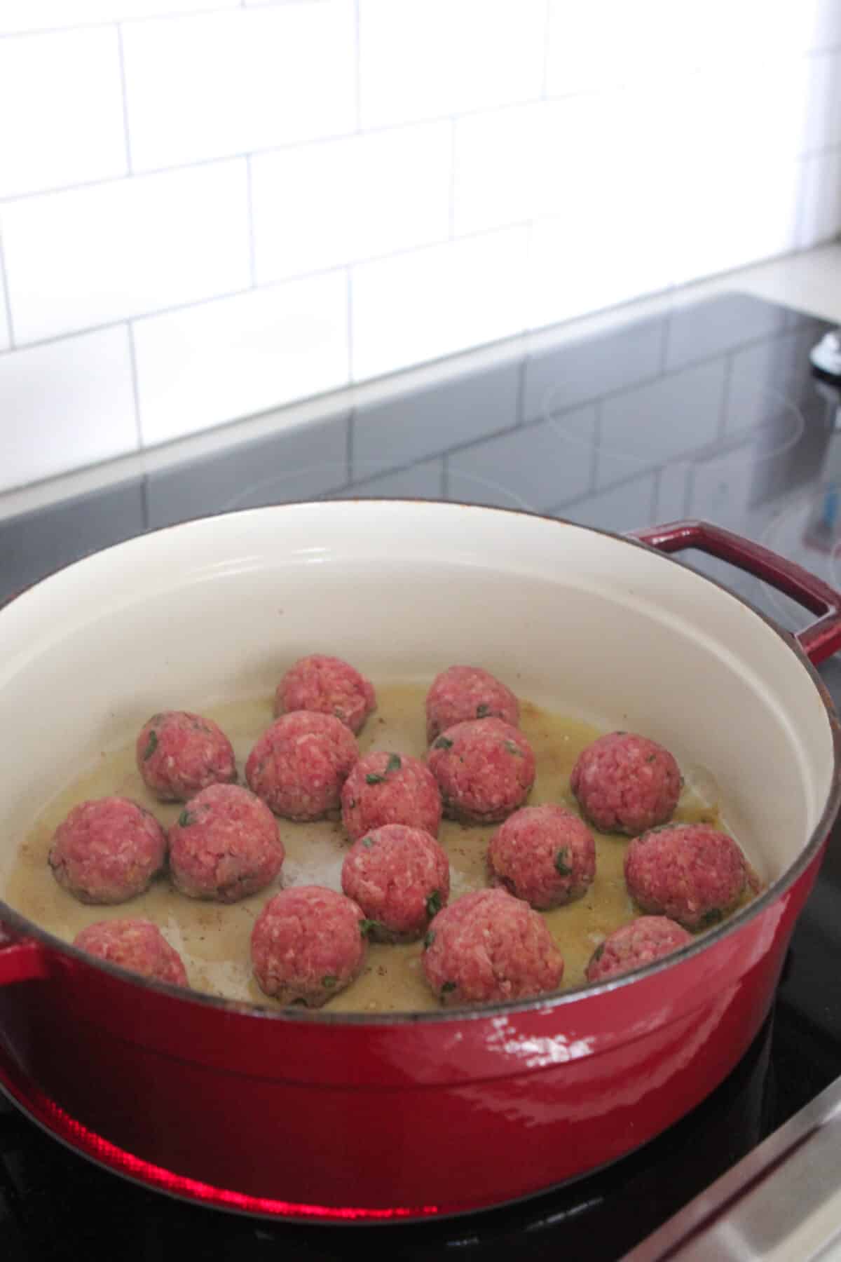 browning meatballs in pan with olive oil