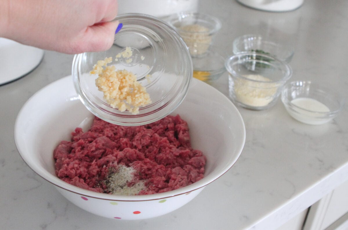 adding minced garlic to meat mixture