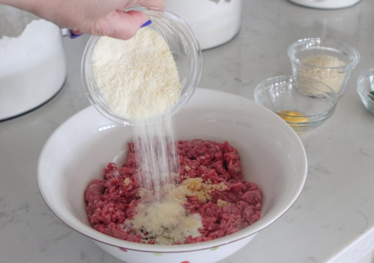 adding parmesan cheese to meatball mixture