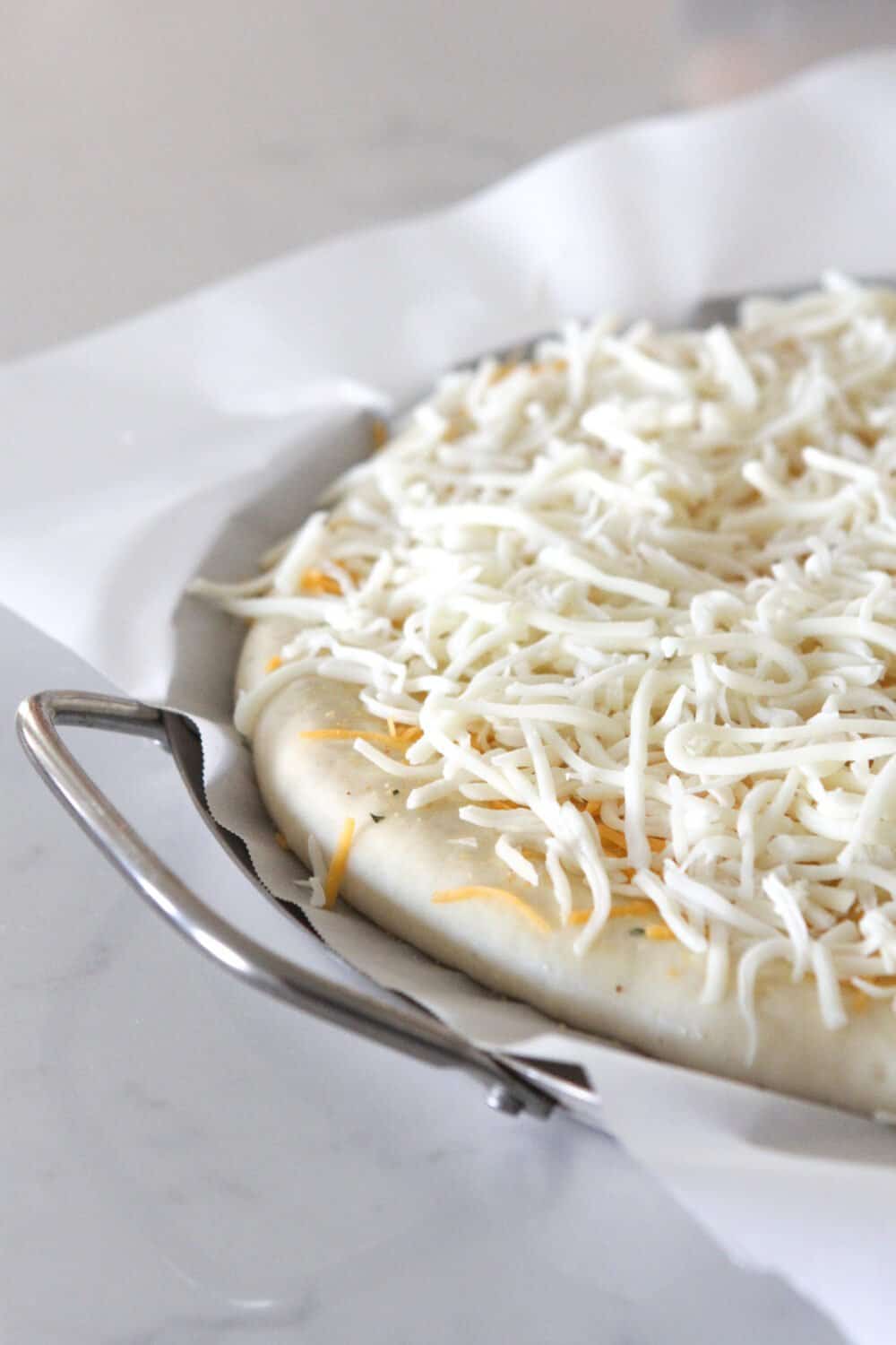 shredded cheese on top of pizza dough