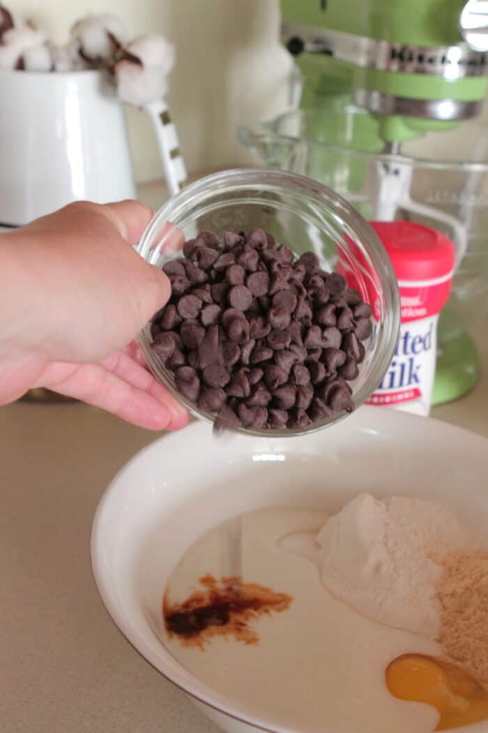pouring chocolate chips into mixing bowl of pancake batter