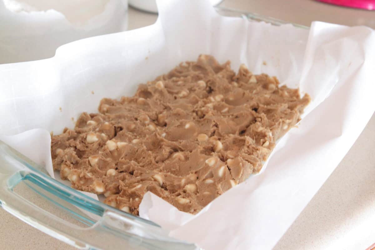 cookie dough pressed into baking dish for cookie dough
