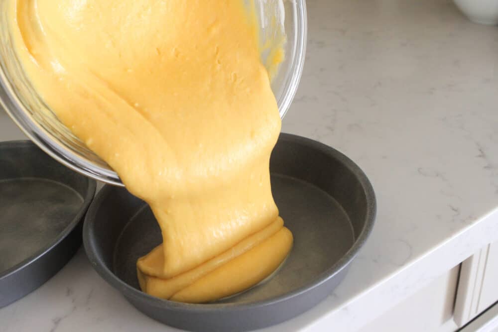 pouring cake batter into cake pans