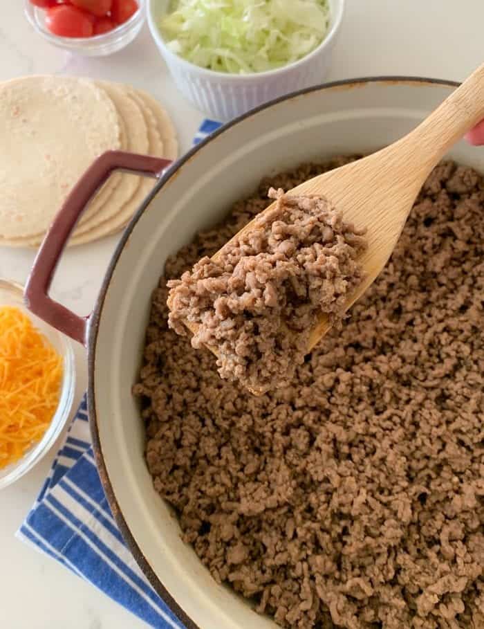 Dutch oven with taco meat and a wooden spoon