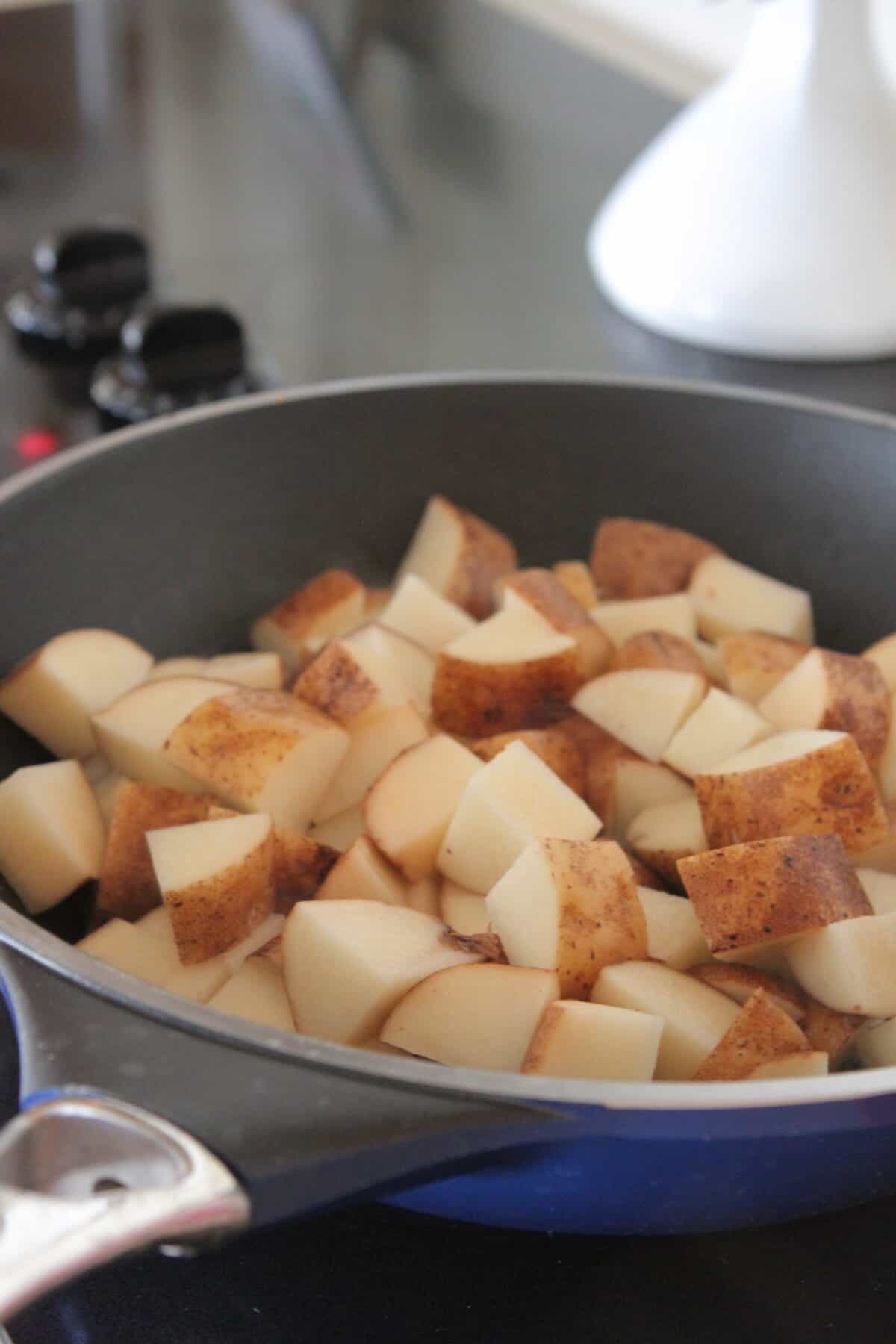 cubed potatoes in hot skillet with olive oil