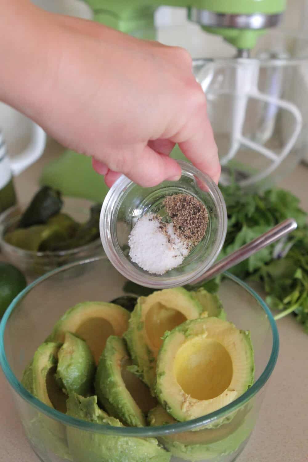 adding seasonings to bowl of avocados