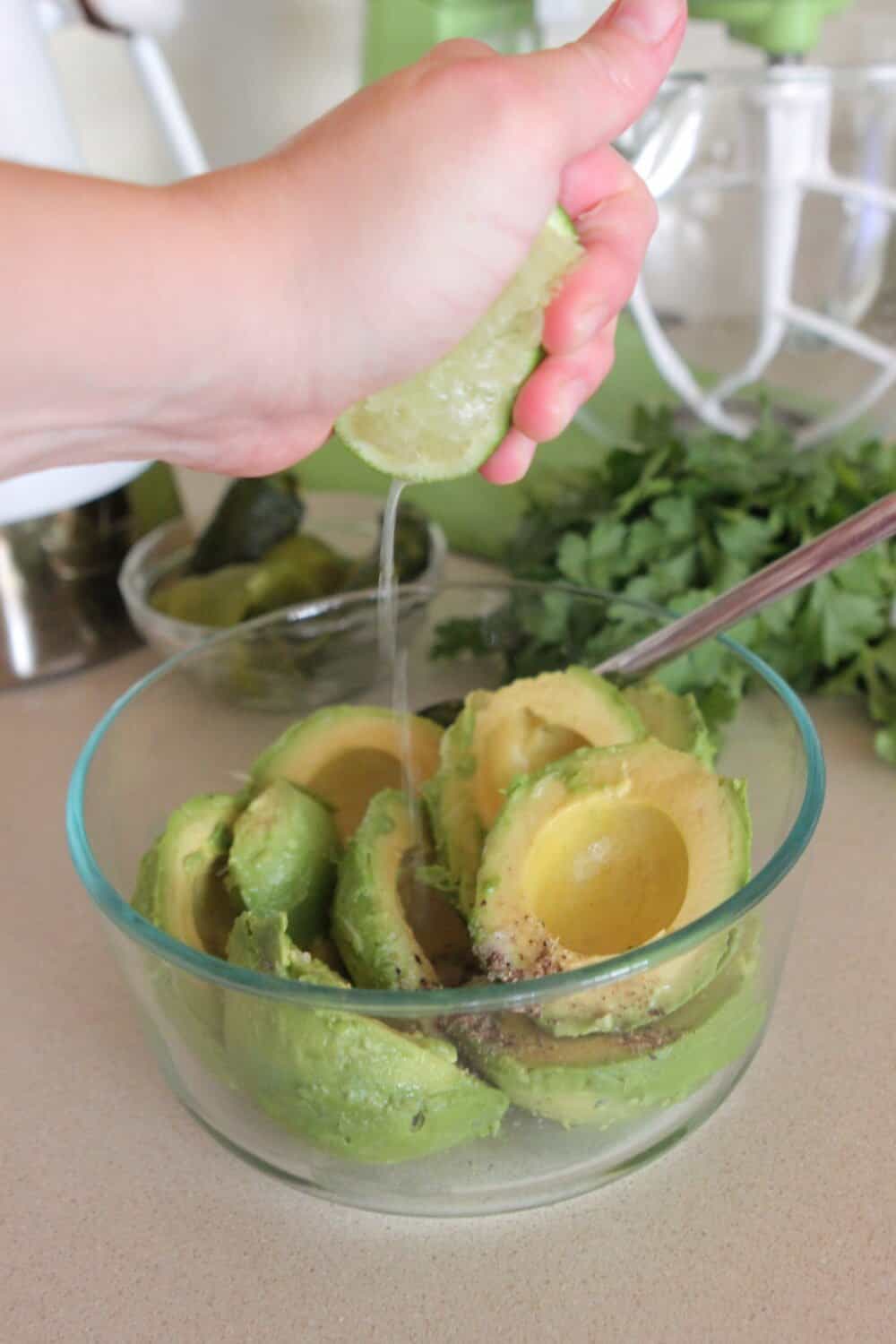 squeezing fresh lime in bowl of avocados