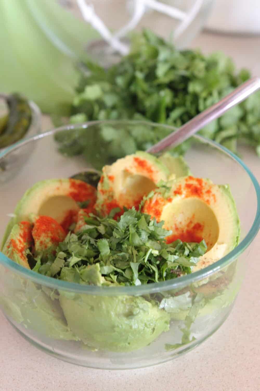cilantro added to bowl of avocados