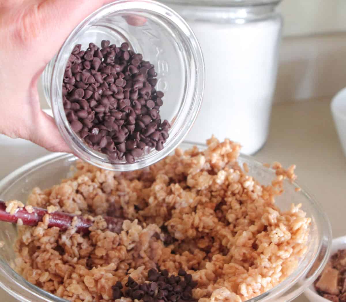 pouring chocolate chips into rice krispie treats