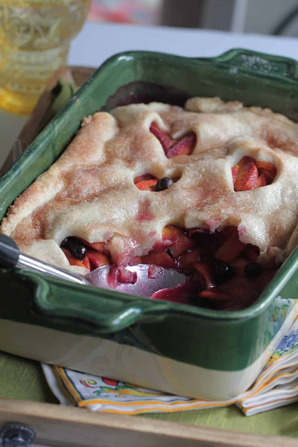 homemade pie dough rolled over peach cobbler baking dish