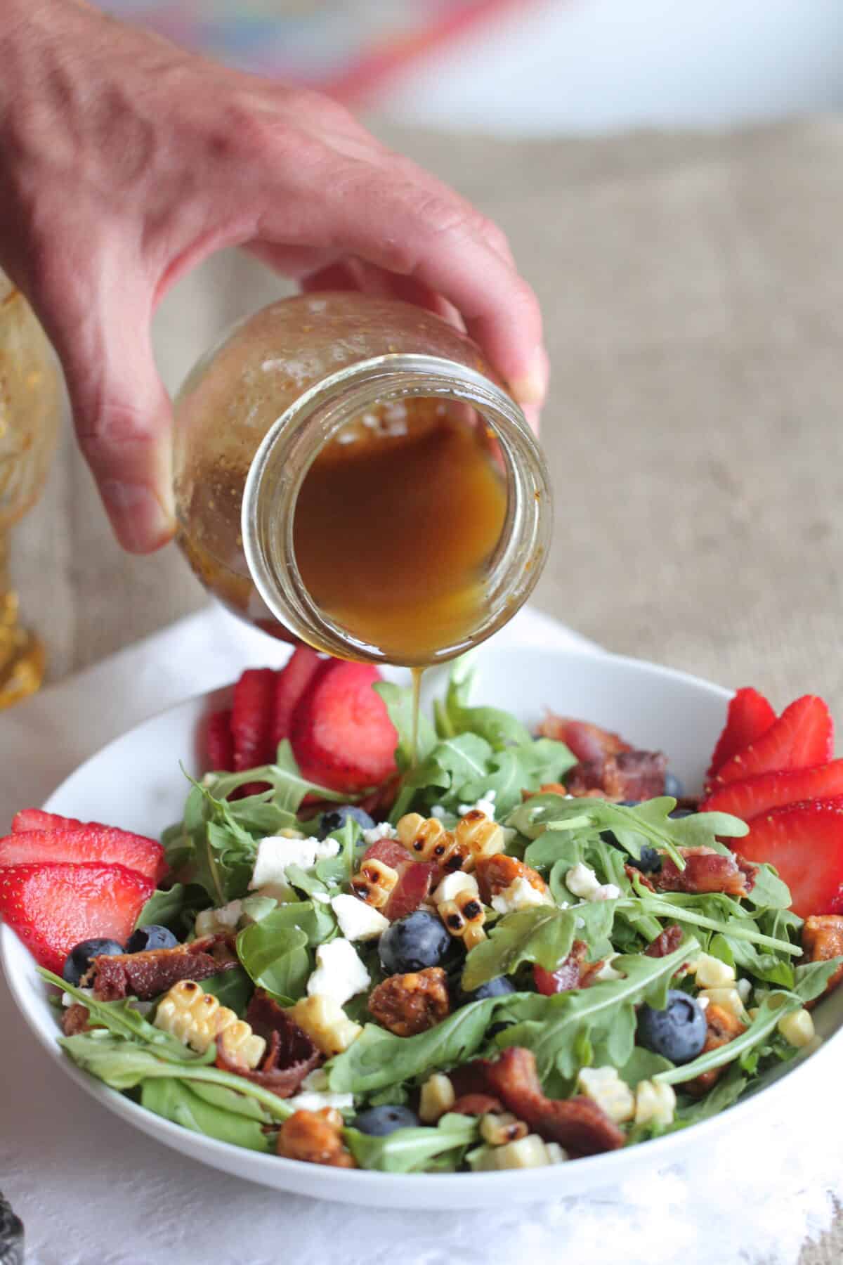 pouring dressing over summer salad