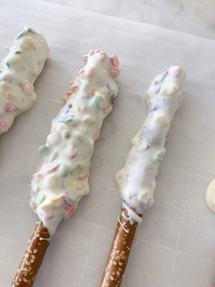 chocolate dipped pretzels setting up on parchment paper