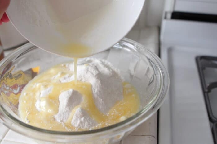 pouring melted butter in bowl of cake mix