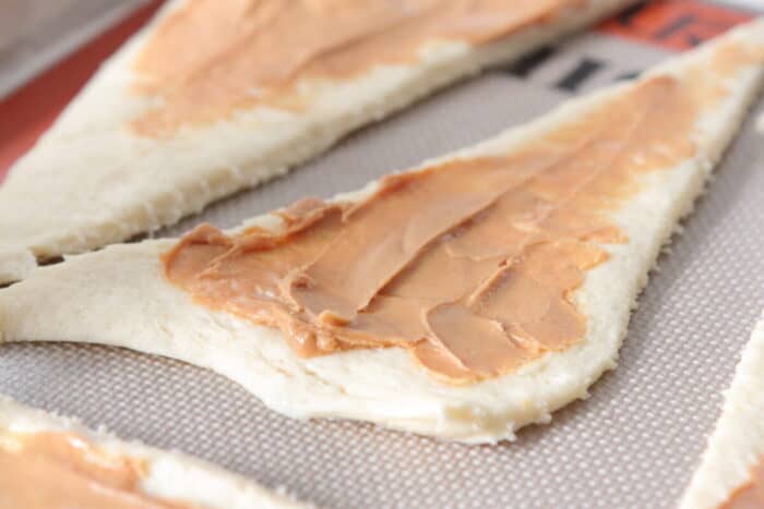 peanut butter spread over crescent rolls on baking sheet