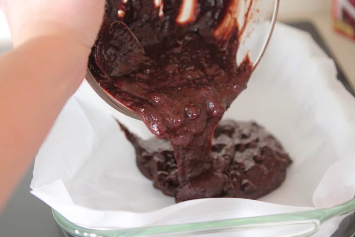 pouring brownie batter in baking pan