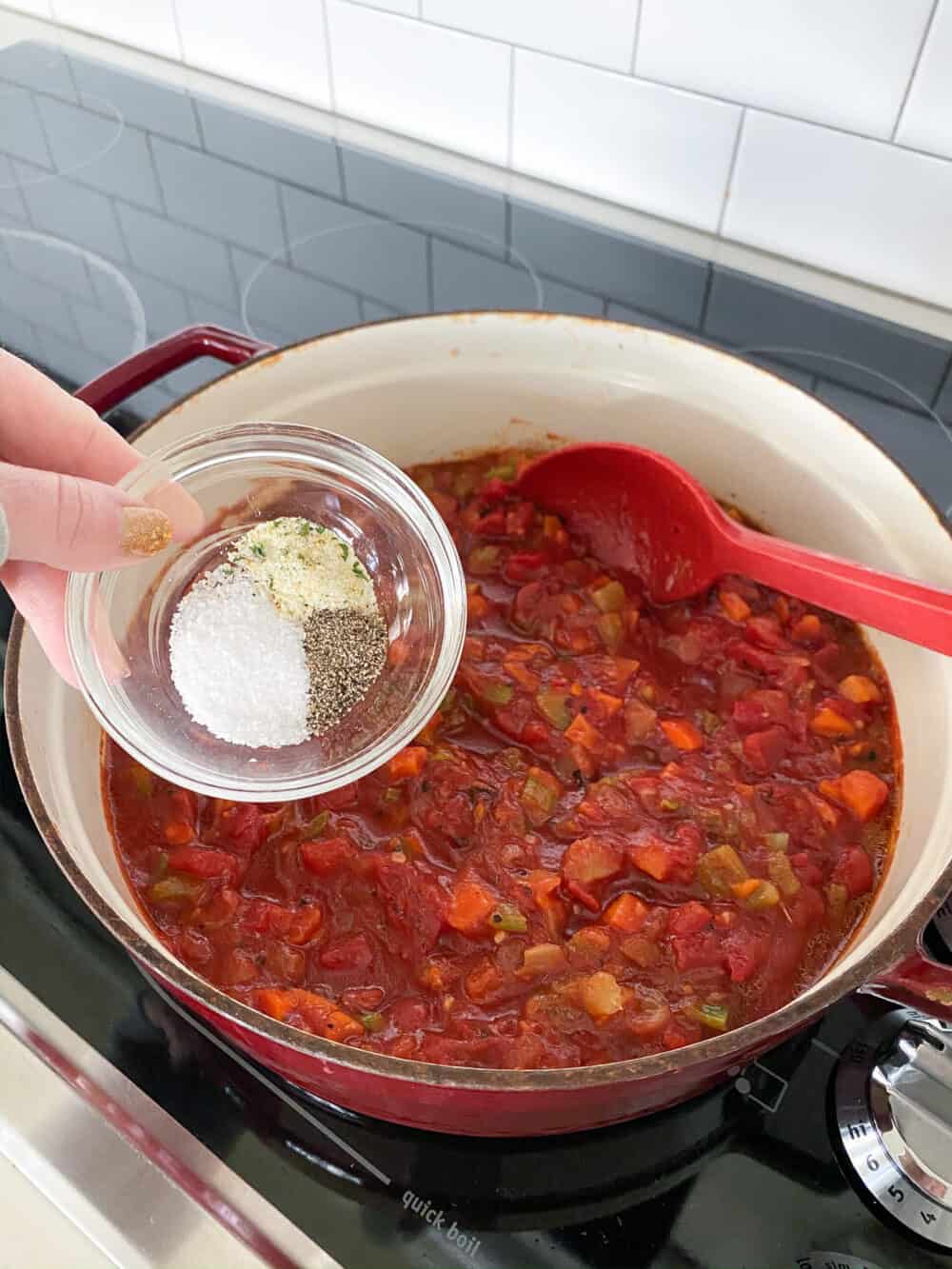 adding seasonings to pot of tomato bisque