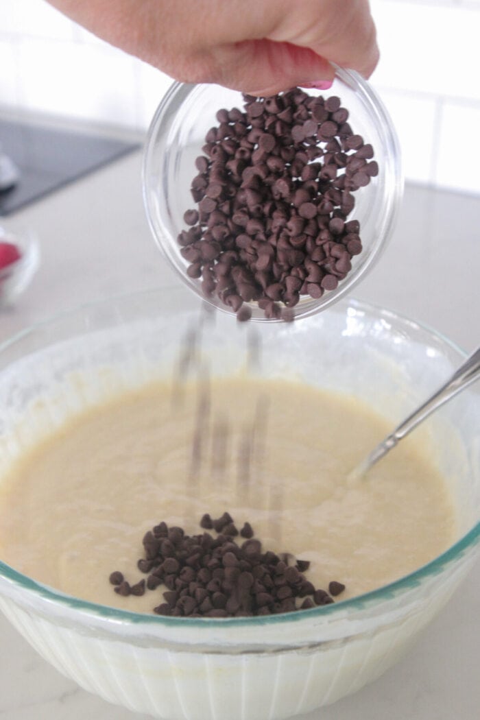 pouring chocolate chips into mixing bowl for pancakes