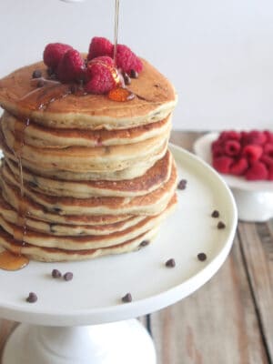 pouring syrup over raspberry chocolate chip pancakes