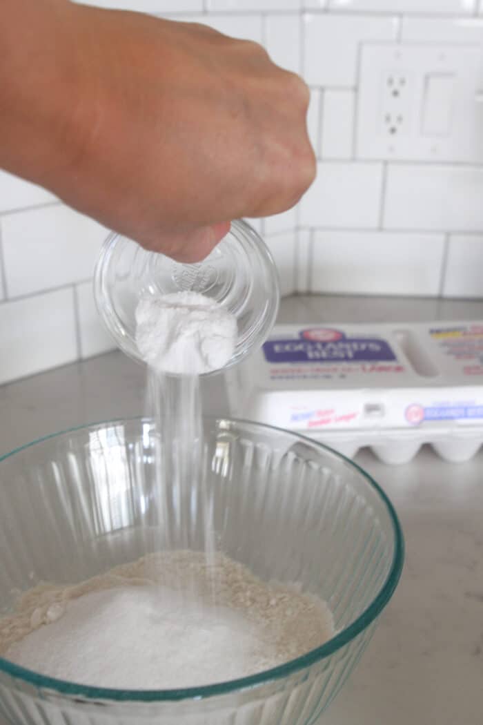 pouring baking soda into mixing bowl for homemade pancakes