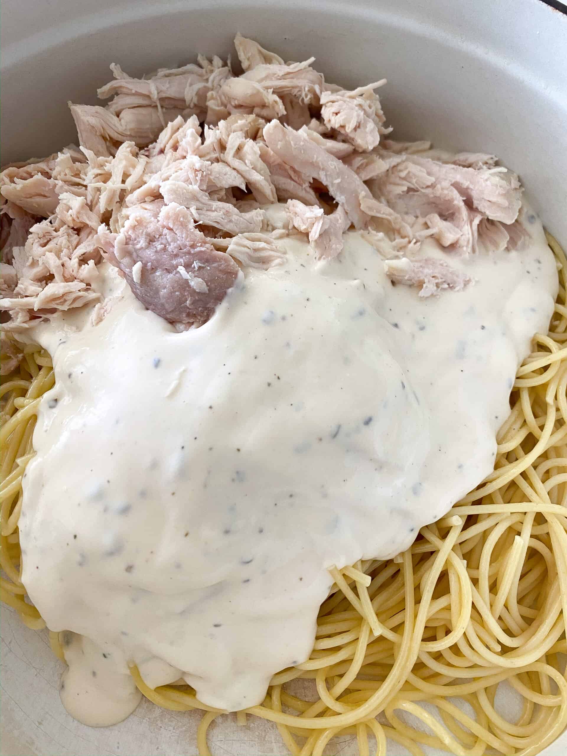alfredo sauce over chicken and noodles in baking dish