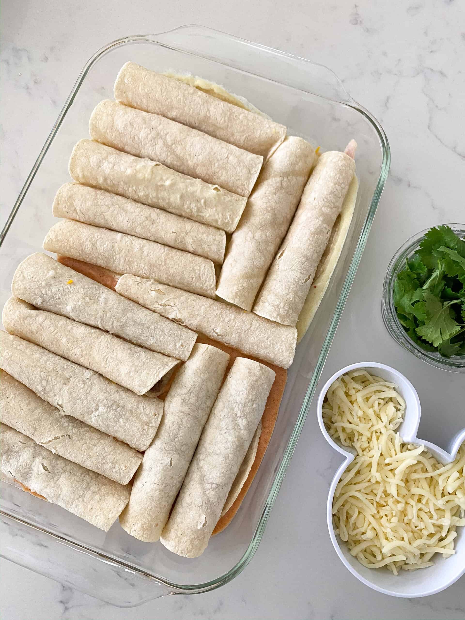 add sauce over rolled enchiladas in pan