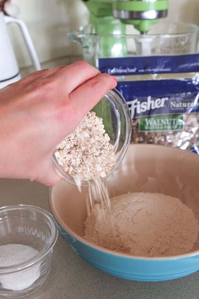 pouring oats into dry ingredient bowl for homemade pancakes