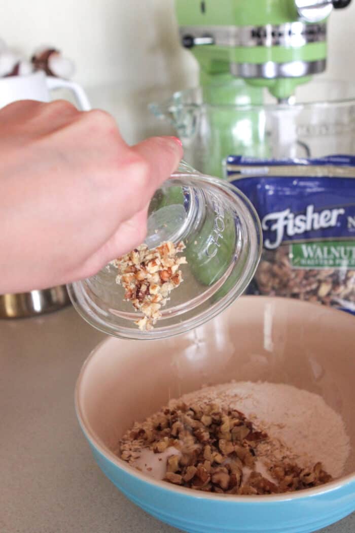 pouring walnuts in dry ingredient bowl for homemade pancake recipe