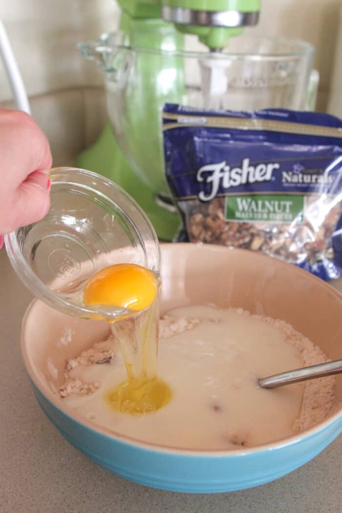 pouring egg into mixing bowl for homemade pancakes