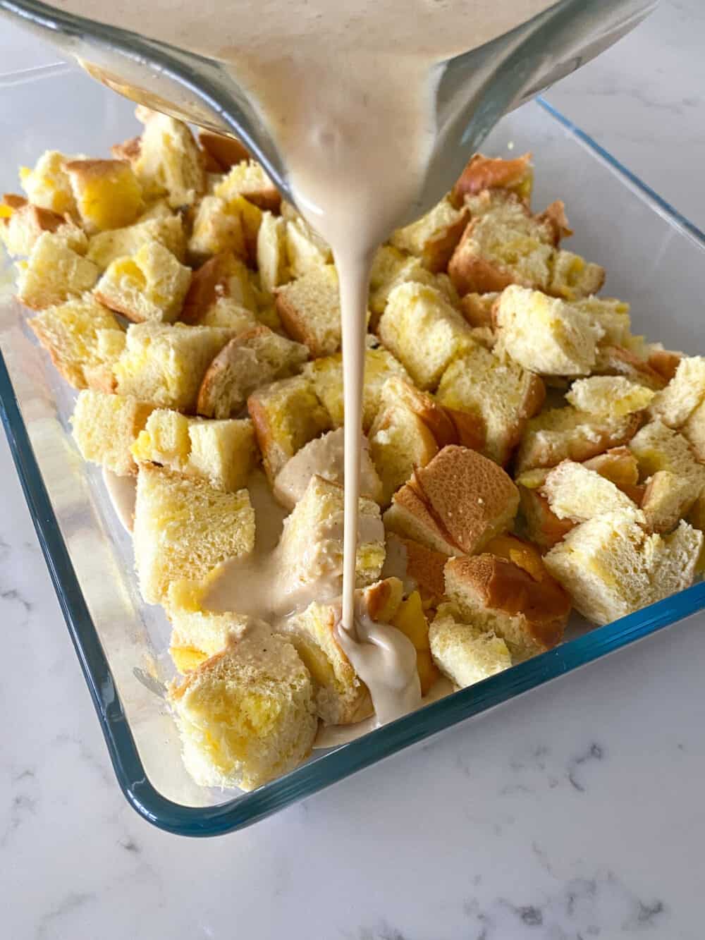 pouring egg mixture over cinnamon roll french toast bake