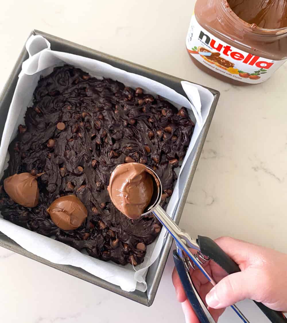 pouring batter into baking dish for nutella brownies
