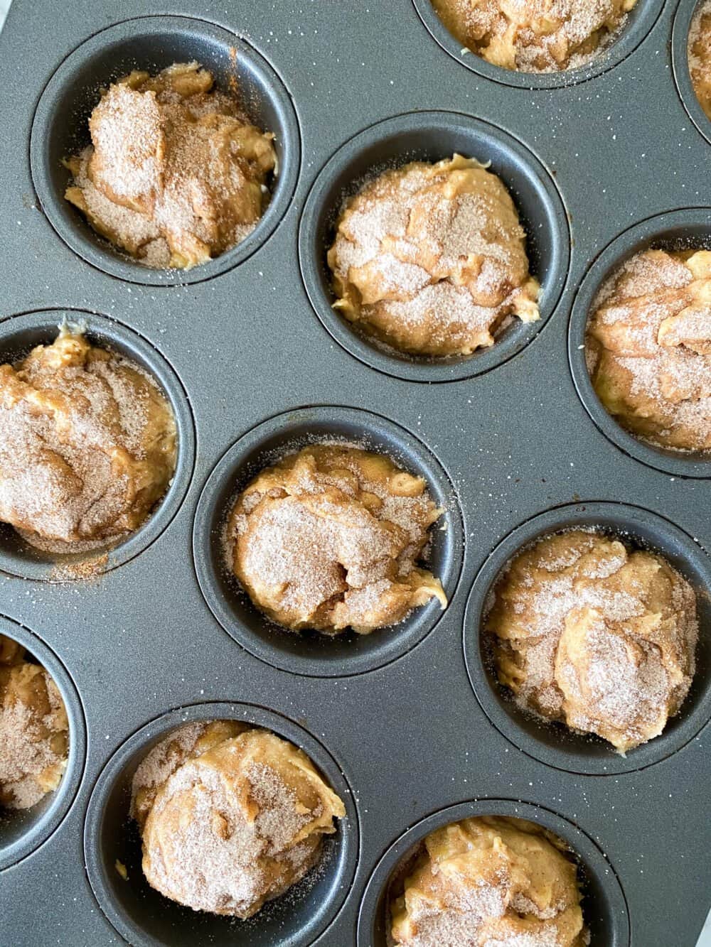 filling banana bread muffin batter into muffin tins