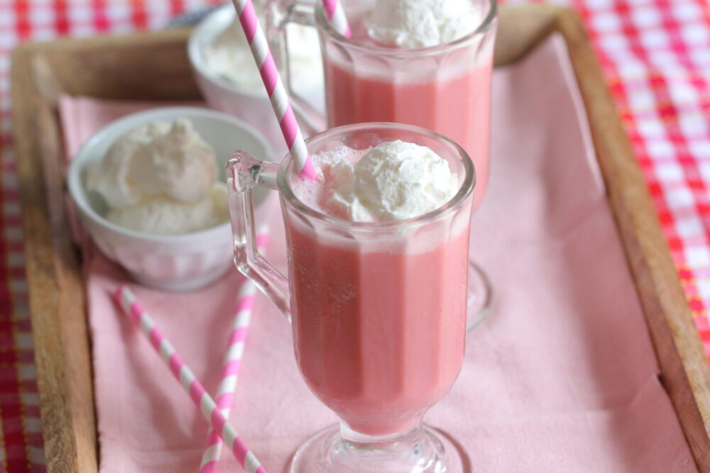 frozen strawberry milk in glass with whipped cream on top
