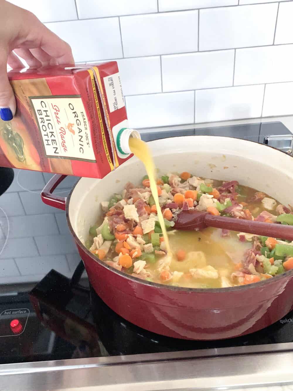 adding chicken broth to soup pot 