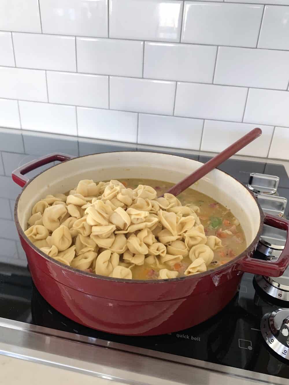 tortellini added to soup pot