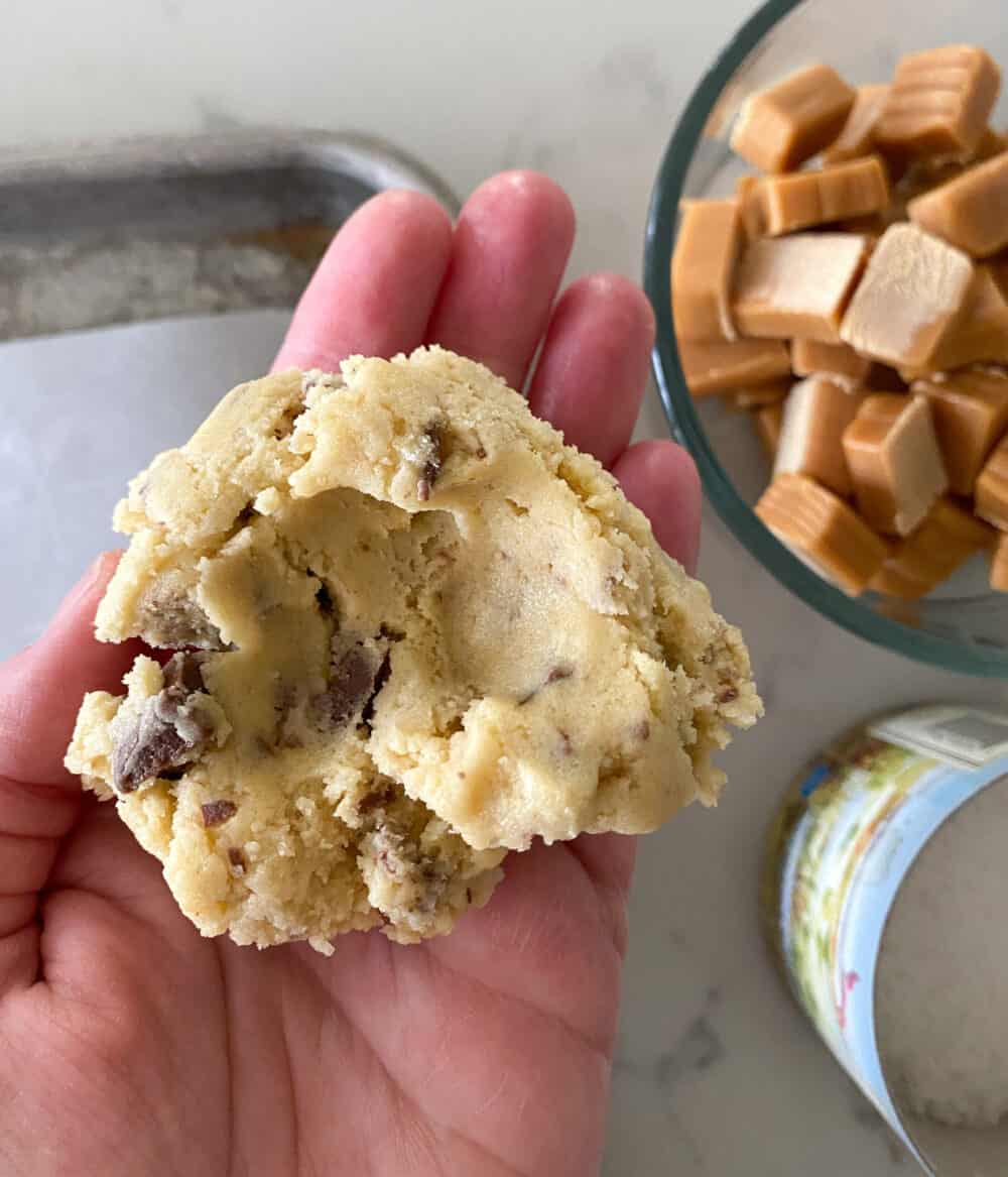 holding cookie dough to stuff caramel for salted caramel cookies