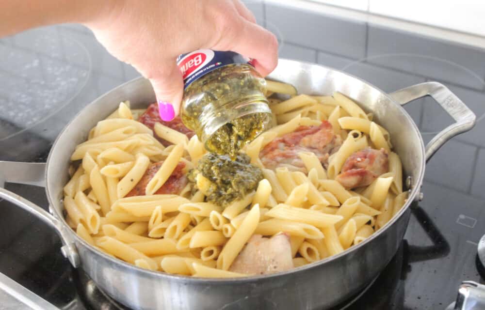 adding pesto to pot of pasta