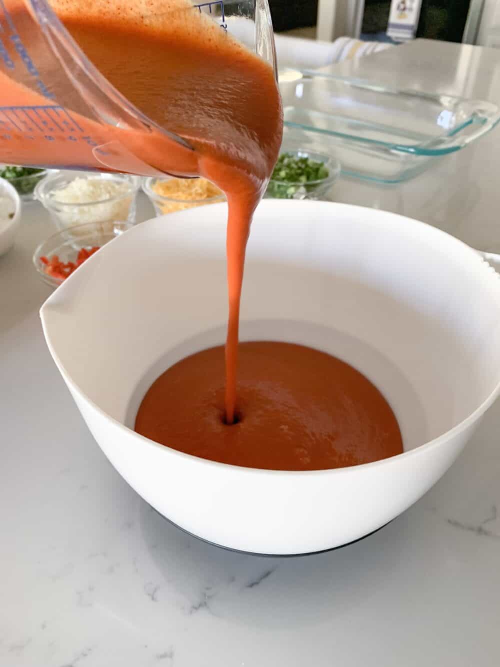 pouring enchilada sauce in bowl