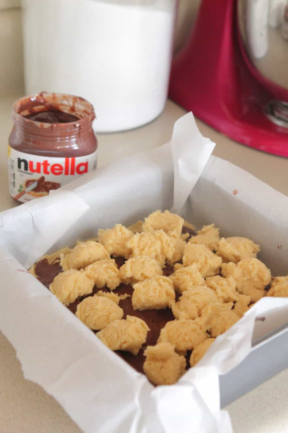 cookie dough over nutella in baking pan