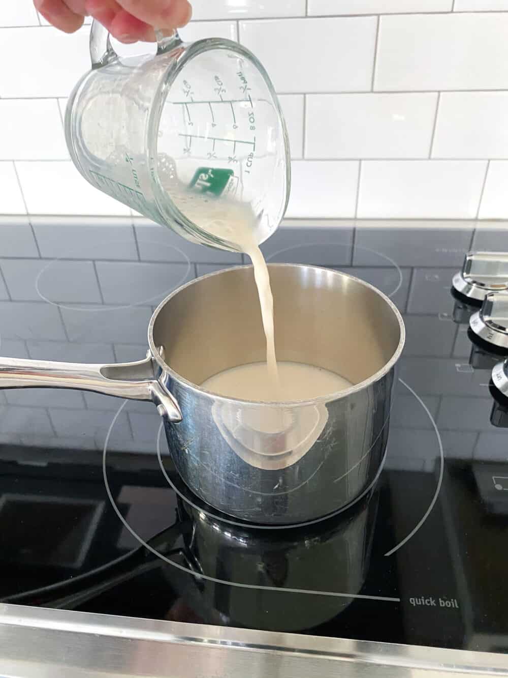 adding almond milk to saucepan over stovetop