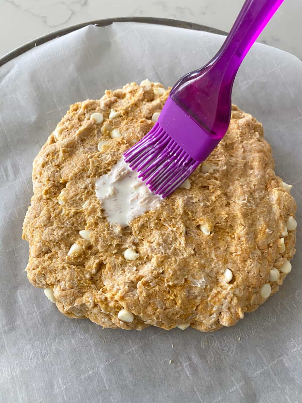 brushing heavy cream on pumpkin scones dough