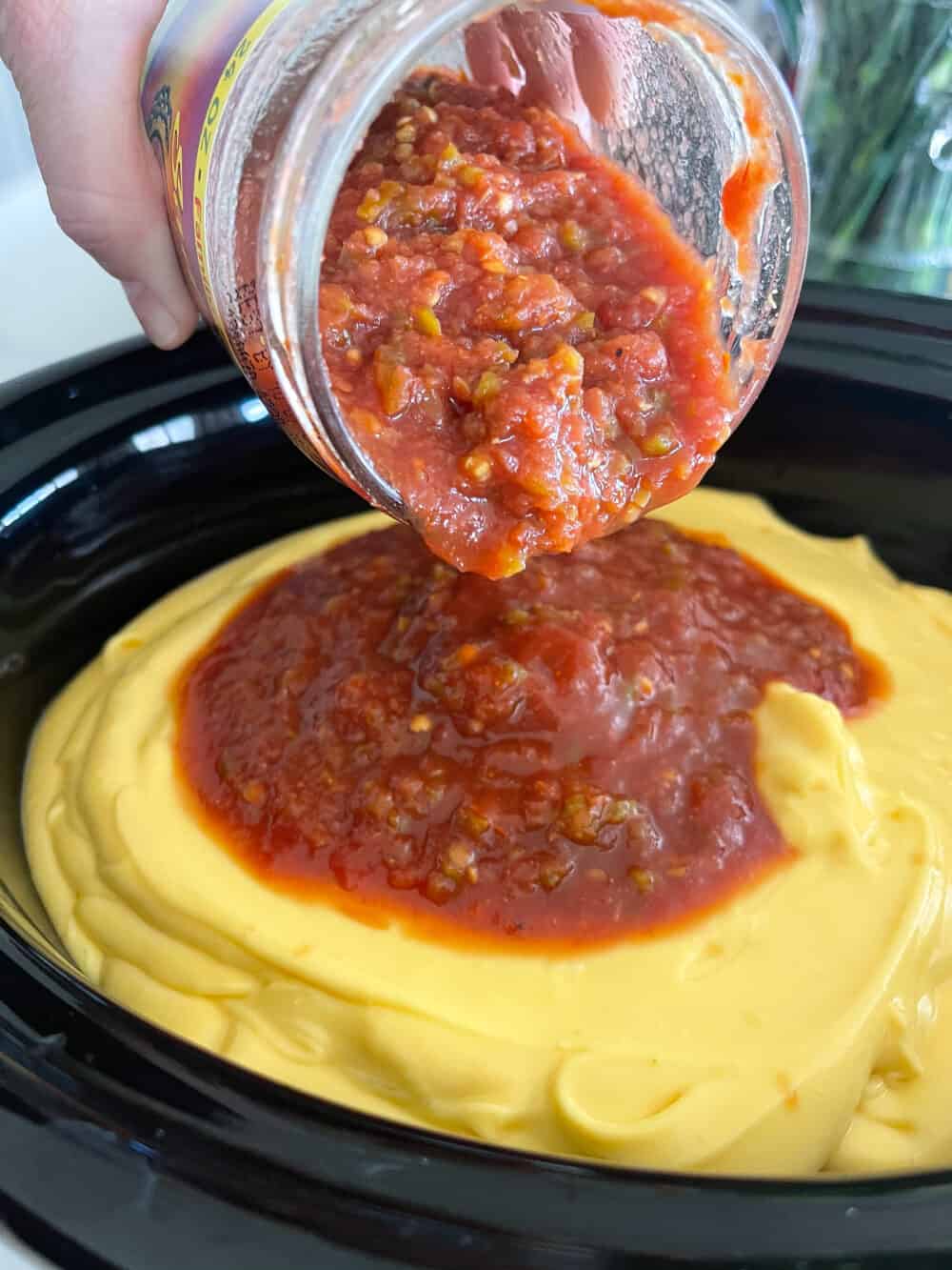 adding salsa to crockpot for queso recipe