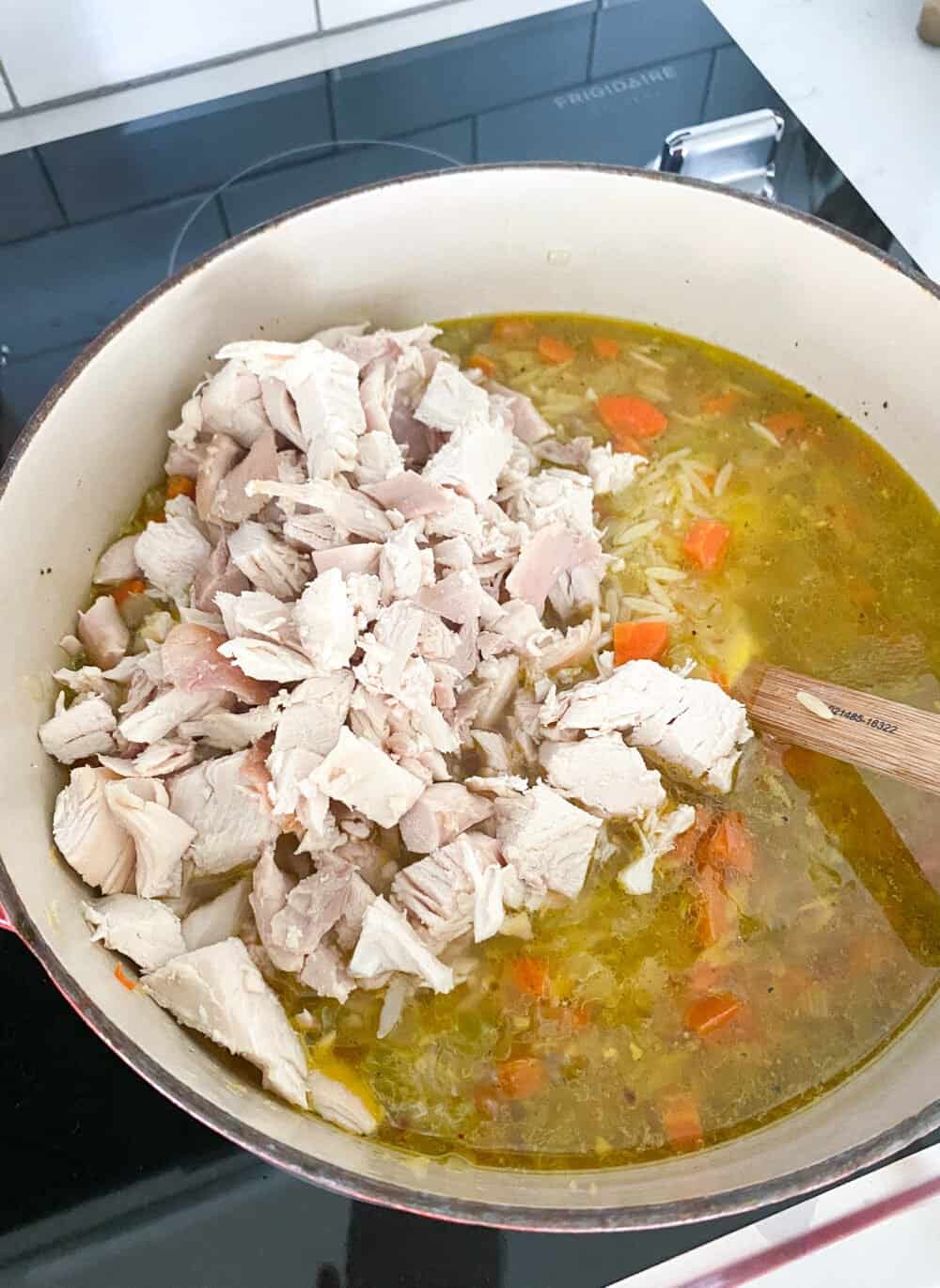 adding cooked chicken to soup pot