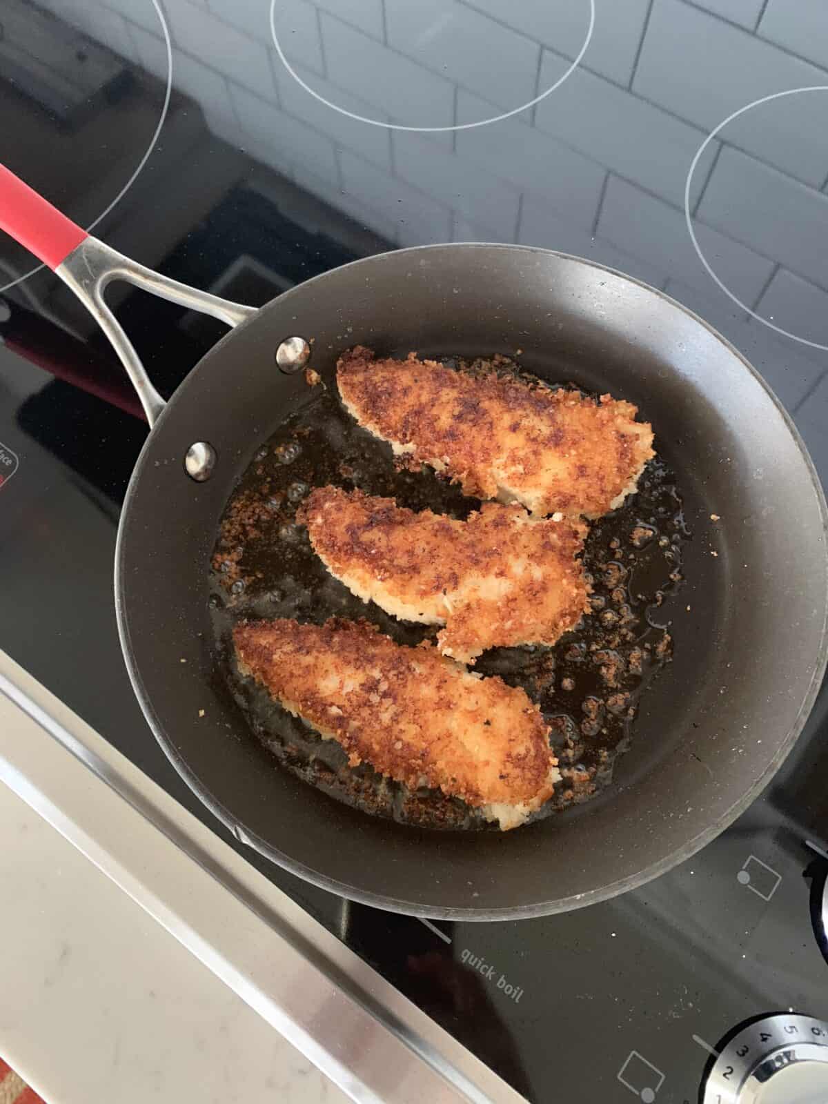 crispy chicken tenders cooking in skillet
