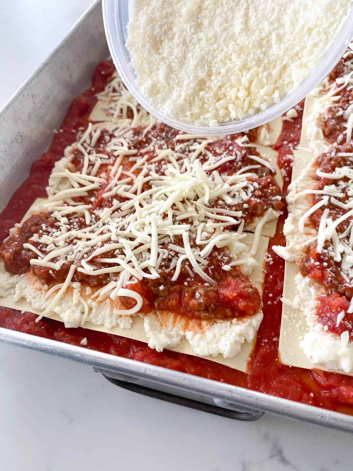 sprinkling cheese over lasagna layers